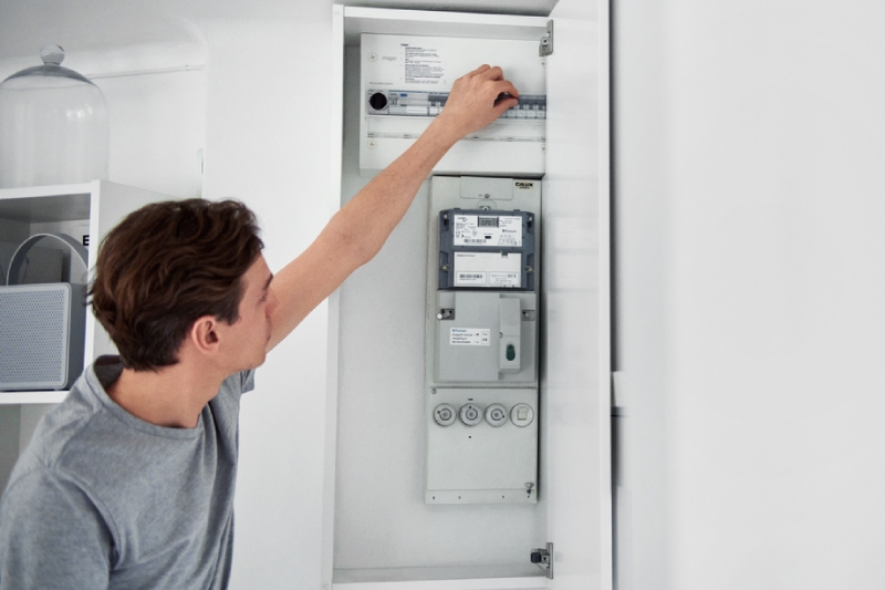 Junger Mann steht an einem Stromzählerkasten