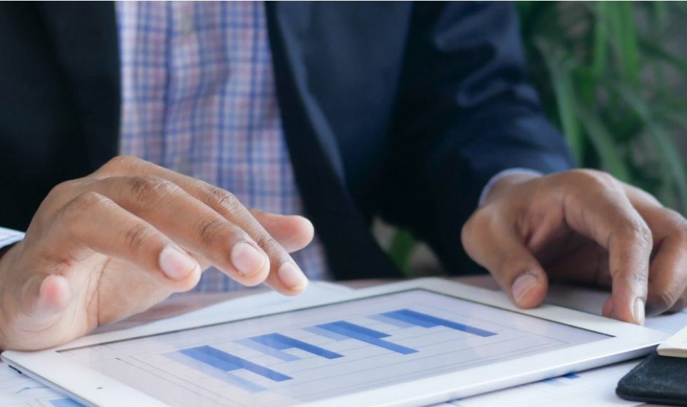 Emissionsfaktoren: Das Foto zeigt Hände in Nahaufnahme, die an einem Tablet mit Balkendiagrammen arbeiten