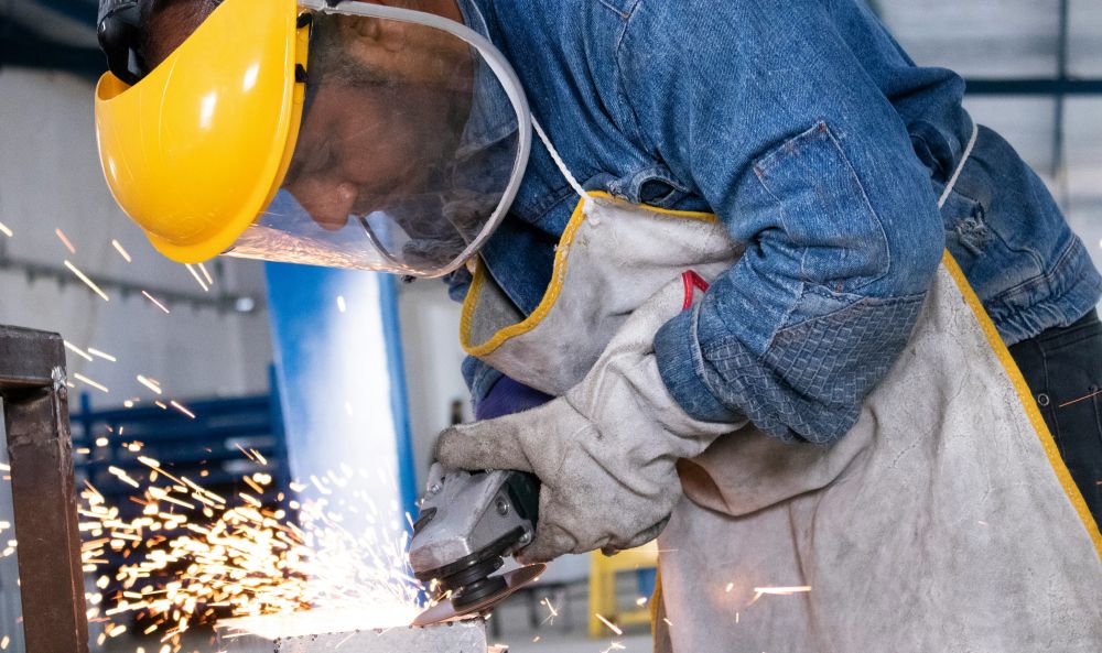 Dieses Bild zeigt einen Arbeiter der einen Winkelschleifer benutzt und verdeutlicht das Thema Industriestrompreis 2025