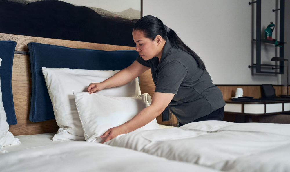 Landhaus Stricker Best Practice - Eine Hotelangestellte streicht ein Bett glatt