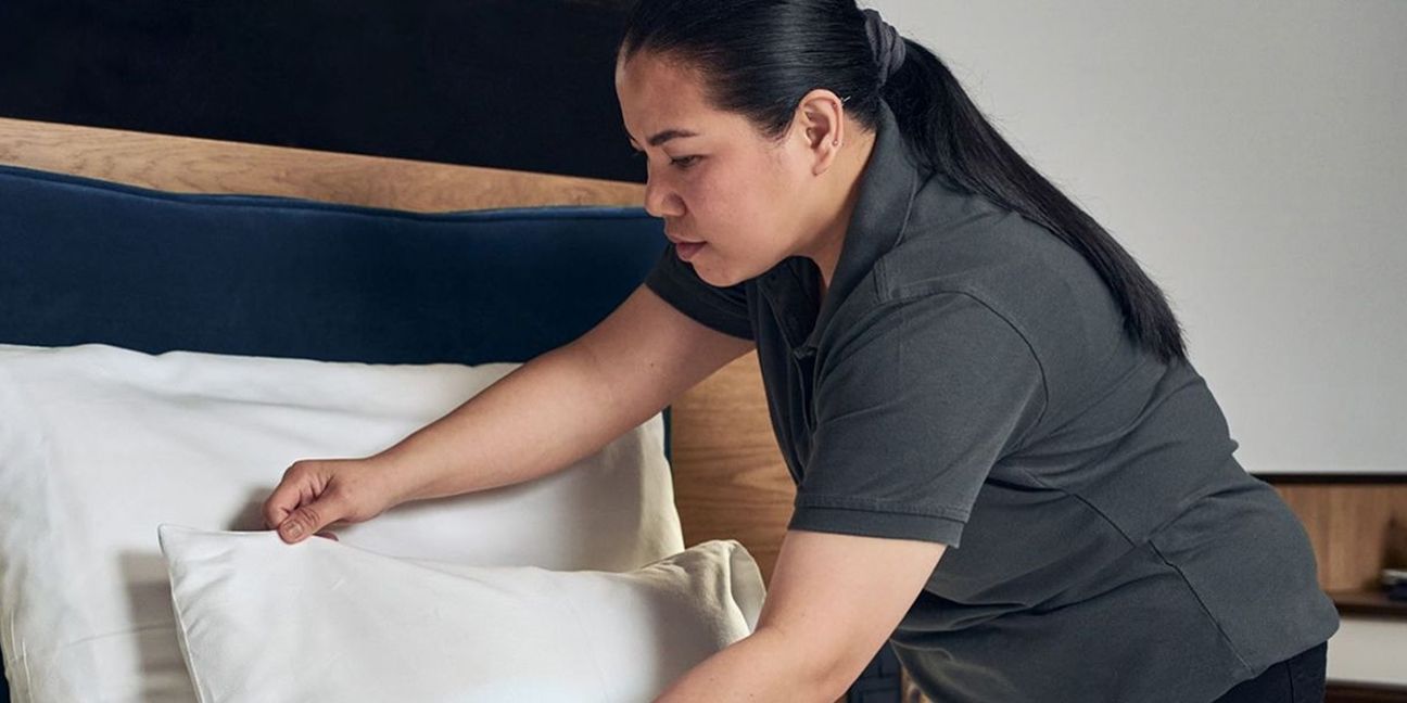 Dieses Bild zeigt eine Hotelangestelle, wie sie ein Bett herrichtet und verdeutlicht das Thema Best Practice Hotellerie Landhaus Stricker