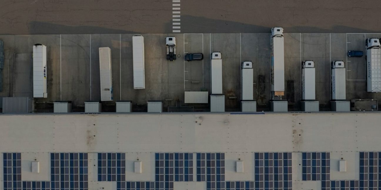 Dieses Bild zeigt LKWs bei der Warenan- und abnahme und verdeutlicht das Thema Lieferkettengesetz