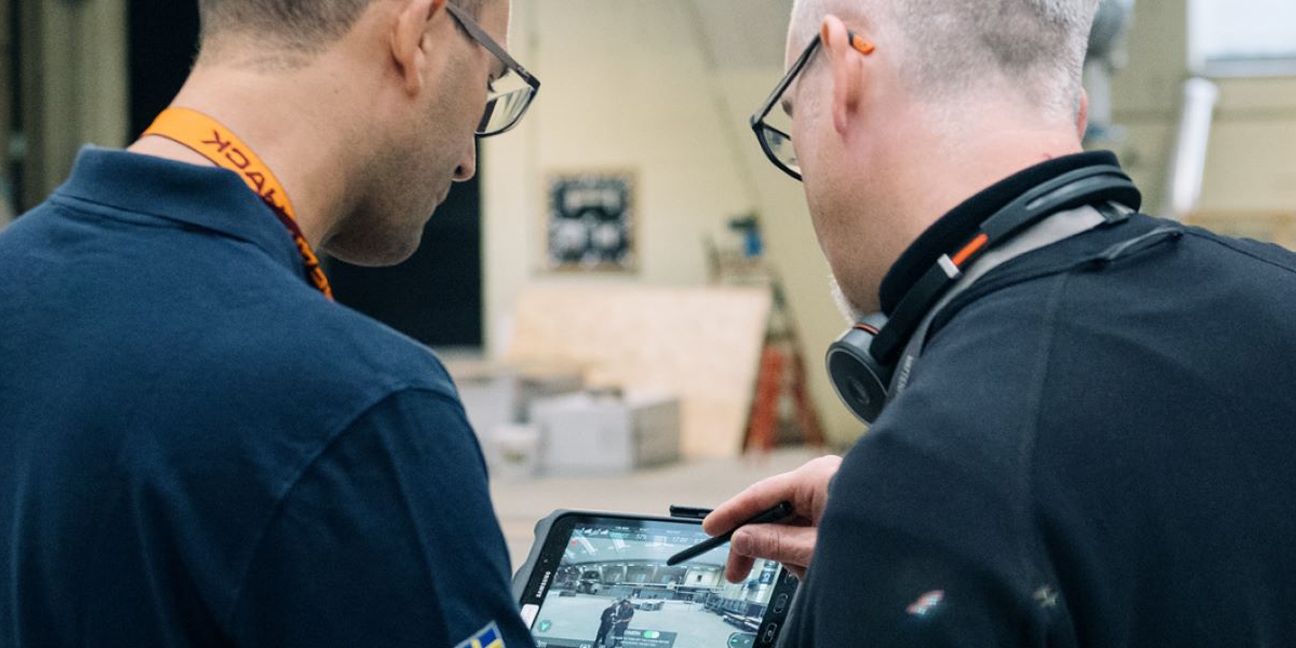 Dieses Bild zeigt zwei Männer an einem Tablet und verdeutlicht das Thema Scope 3: CO2-Bilanz im Unternehmen verbessern und Kosten senken