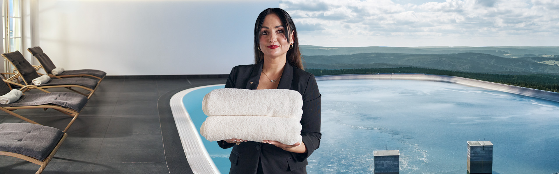Frau hält einen Stapel mit Handtüchern. Im Hintergrund ist ein Pool mit Liegen und eine Landschaft mit Gewässer zu sehen.