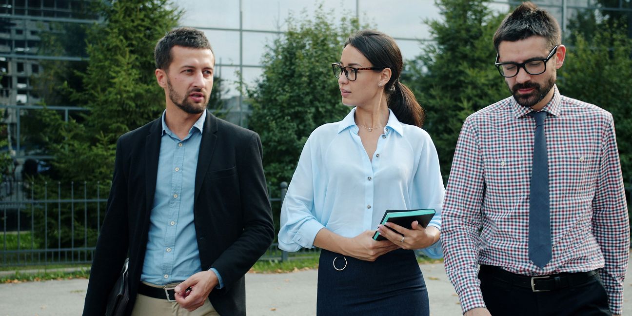 Dieses Bild zeigt drei Menschen vor einem Bürogebäude und verdeutlicht das Thema EMAS Umweltmanagementsystem im Unternehmen