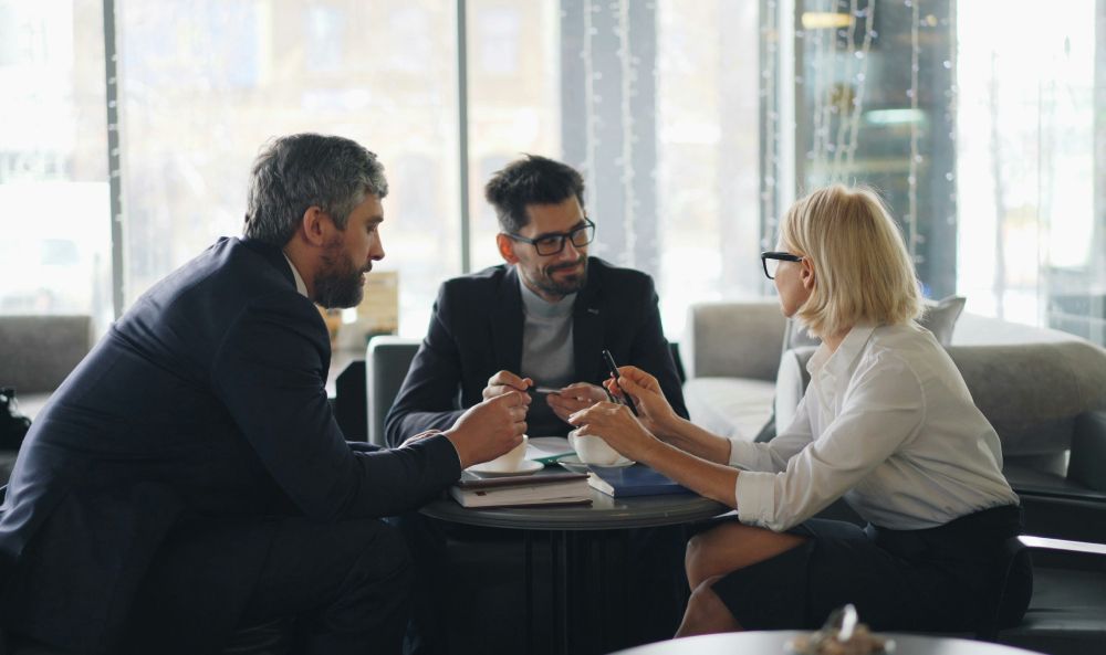 Dieses Bild zeigt drei Menschen bei einem Meeting und verdeutlicht das Thema EMAS Umweltmanagementsystem im Unternehmen