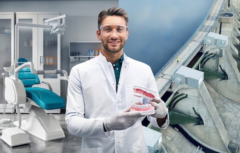 Ein Zahnarzt steht mit einem Gebiss in der Hand in der Praxis.