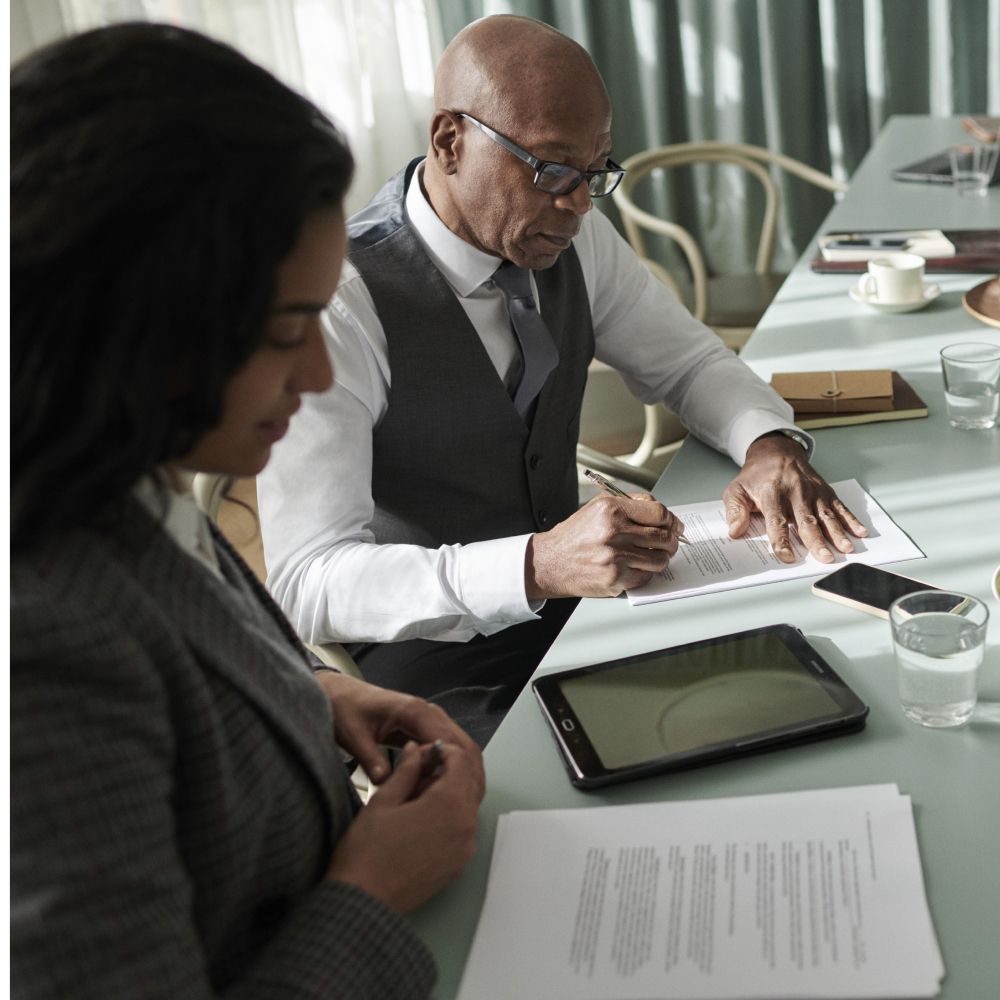 Dieses Bild zeigt zwei Menschen im Büro, die einen Vertrag unterzeichnen und verdeutlicht da Thema EMAS Umweltmanagementsystem im Unternehmen