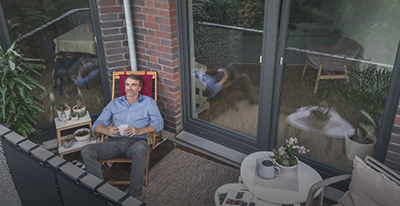 Ein Mann sitzt mit einer Tasse Kaffee auf dem Balkon