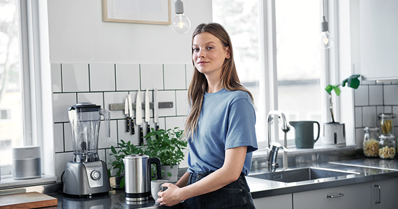 Eine Frau steht in der Küche und lächelt.