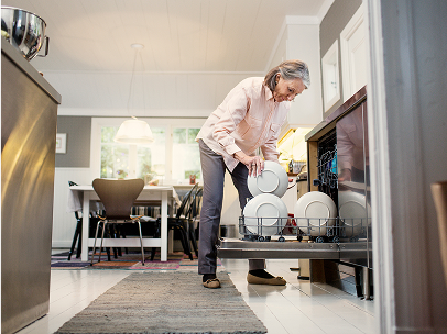 Person räumt in einer modernen Küche eine Spülmaschine ein.
