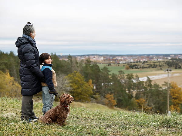 Mutter steht mit Kind und Hund auf einem Hügel
