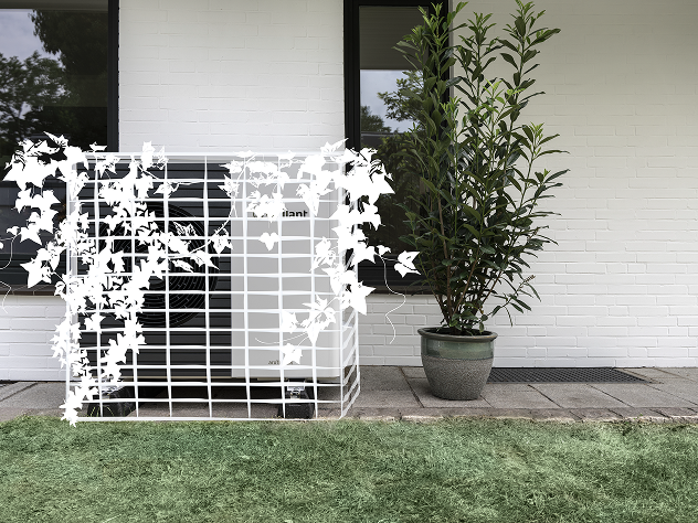 Das Bild zeigt eine Wärmepumpe, die weiß übermalt wurde, um zu demonstrieren, wie sie in die Umgebung integriert und optisch versteckt werden kann. Sie steht vor einer Wand, neben einer Pflanze und auf Rasen.