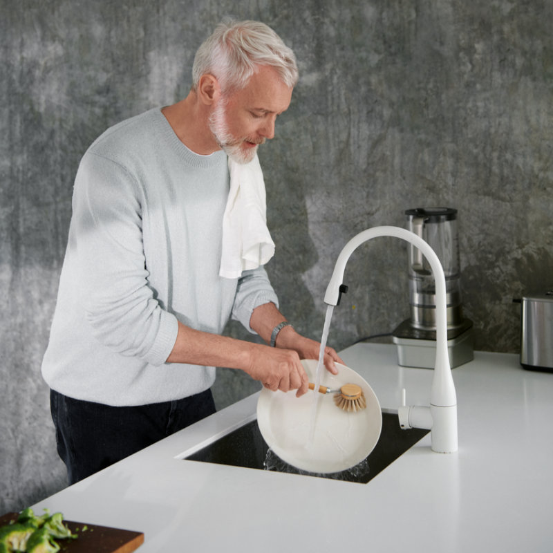 Mann mittleren Alters macht den Abwasch.