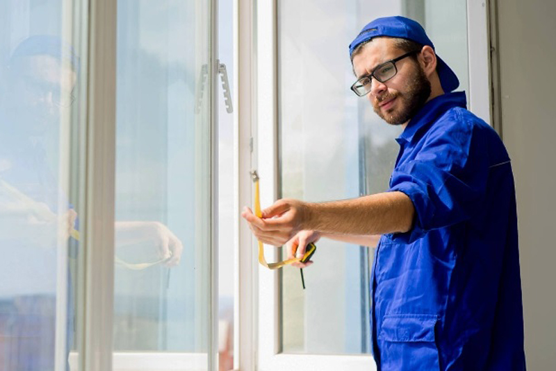 Ein Monteur misst das Fenster aus.