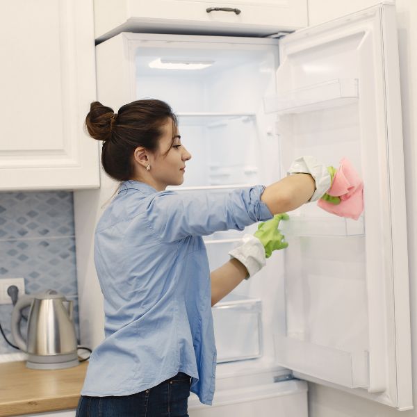 Frau putzt einen Kühlschrank