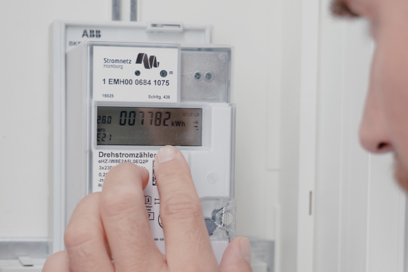 Person überprüft am digitalen Stromzähler den Stromverbrauch.