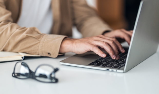 Mann tippt etwas am Computer ab