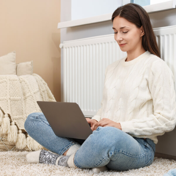 Frau lehnt an einem Heizkörper