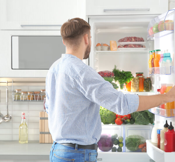 Mann öffnet einen Kühlschrank