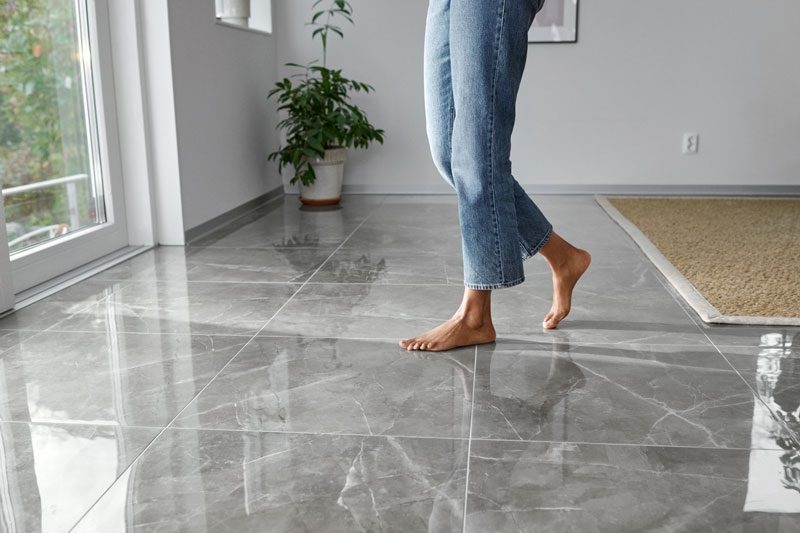 Zwei Füße gehen Barfuß über Mamorfliesen