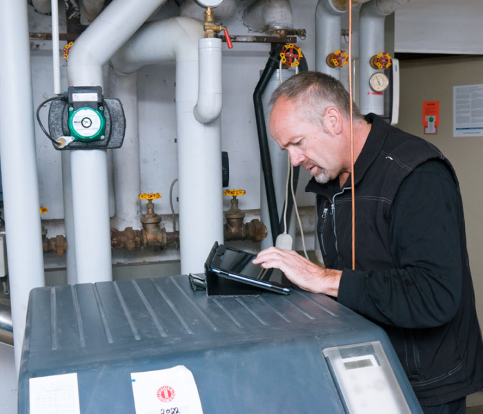 Mann prüft Hybridheizung in einem Keller