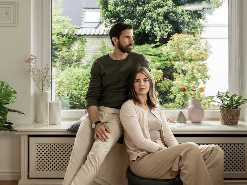 Paar steht neben einem Heizkörper