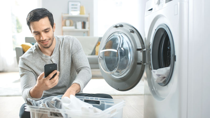 Mann hockt vor Waschmaschine