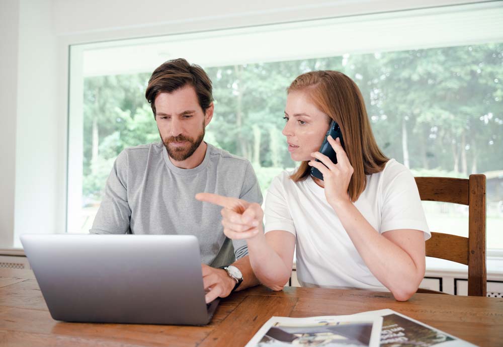 Mann und Frau am Laptop mit Telefon