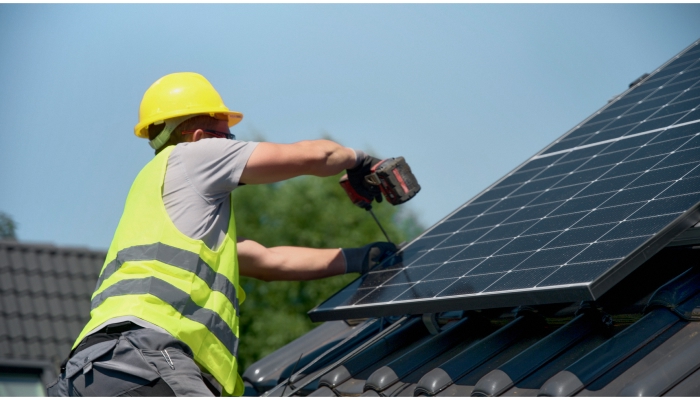 Bauarbeiter montiert ein Solarpanel auf einem Dach