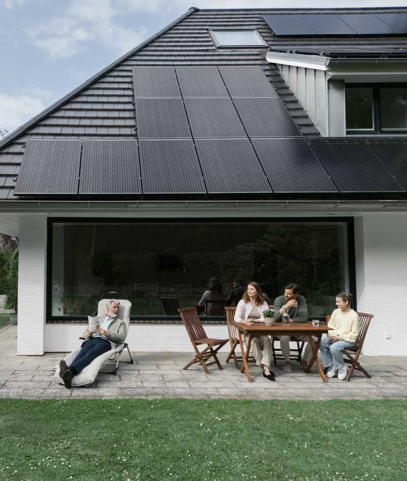 Familie sitzt vor einem Haus im Garten