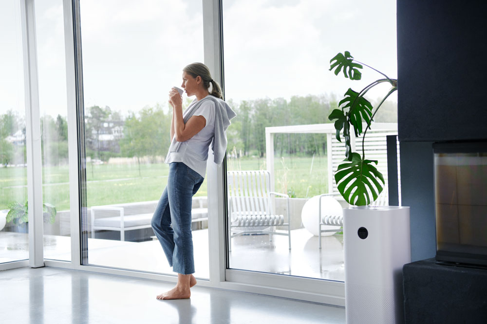 Frau lehnt am Fenster mit einer Tasse in der Hand