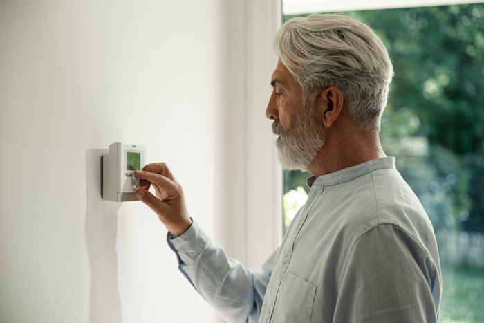 Mann dreht an Temperaturregler