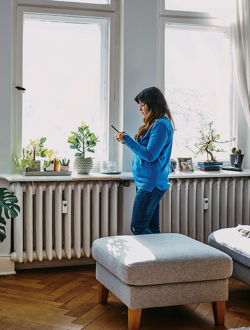 Frau bedient Smartphone neben Fenster