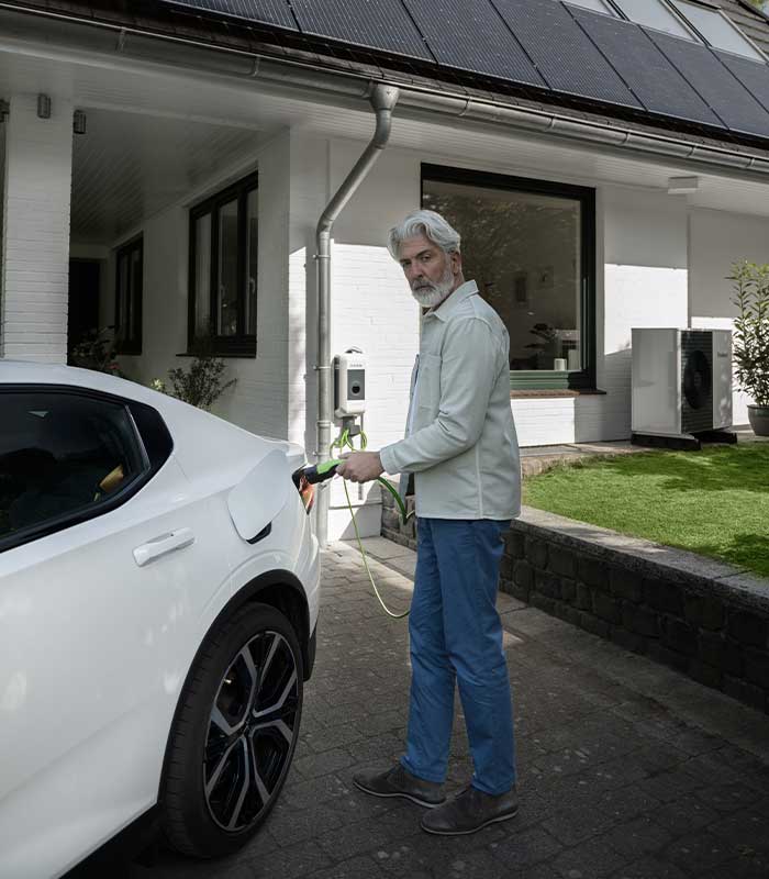 Mann steckt Ladekabel ins Auto