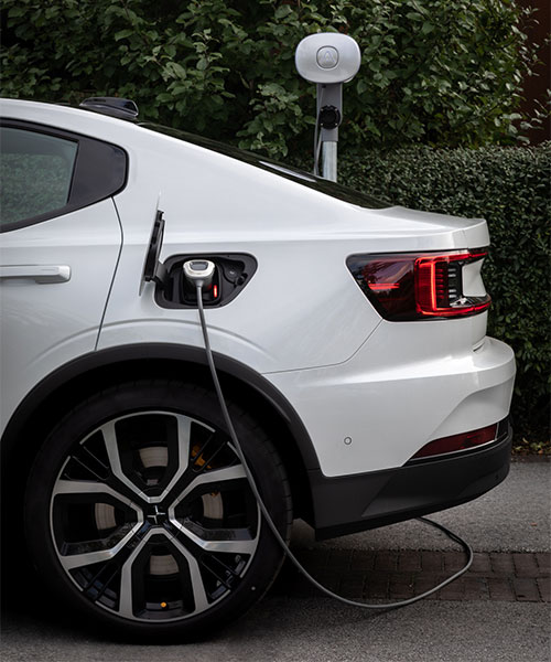 Weißes Elektroauto lädt an Ladestation