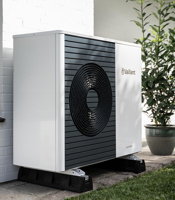 Wärmepumpe steht neben Pflanze