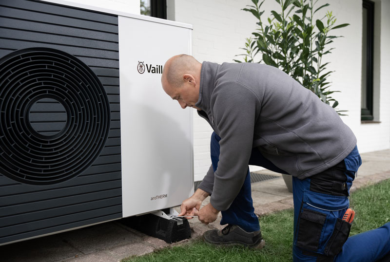 Installateur kniet vor Wärmepumpe