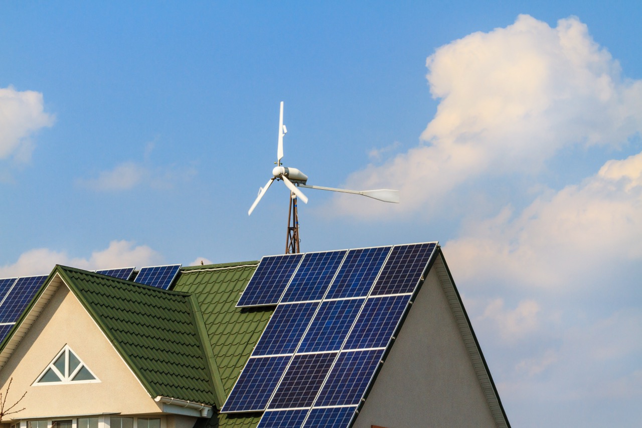 Kombination aus Windrad und PV-Anlage auf Haus – erneuerbare Solar- und Windenergie.