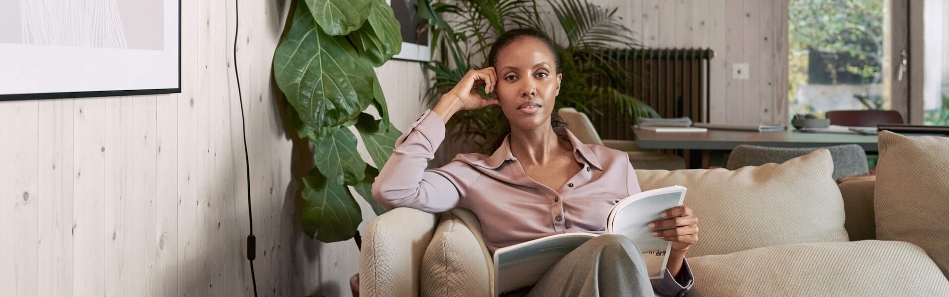 Frau sitzt mit Buch auf der Couch