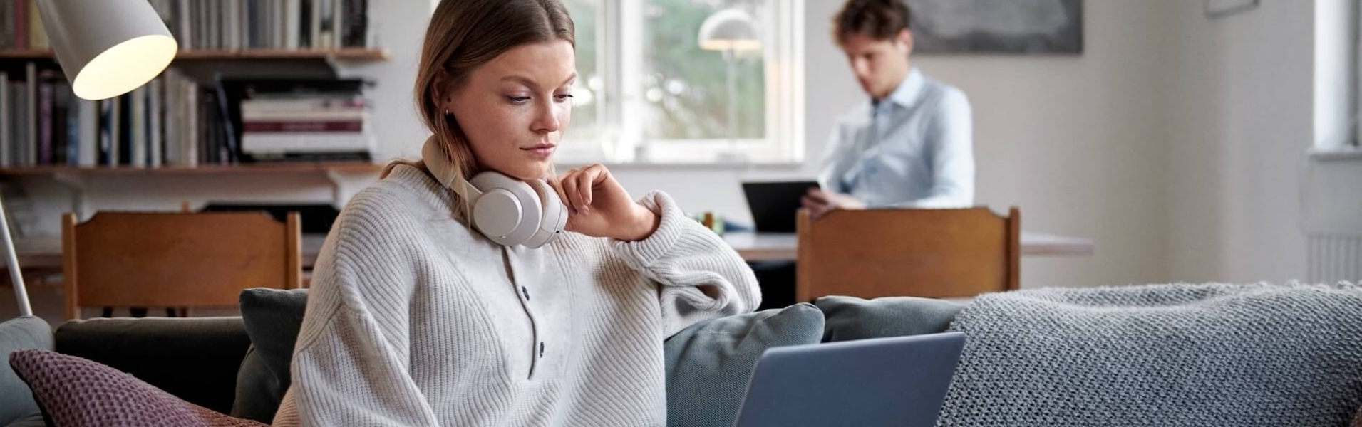 Frau sitzt vor dem Laptop auf dem Sofa