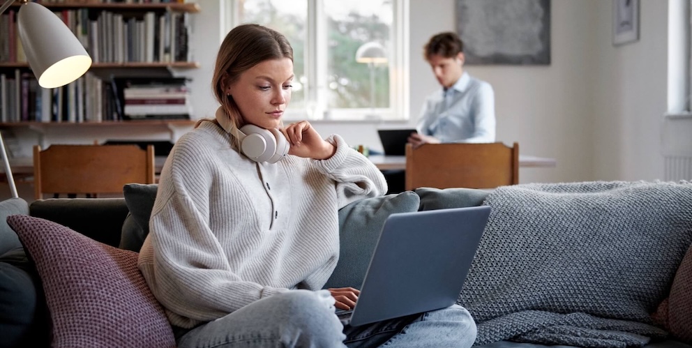 Frau sitzt vor dem Laptop auf dem Sofa