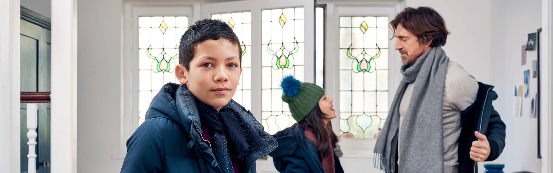 Eine Familie steht an der Tür des Hauses und der Sohn schaut in die Kamera.