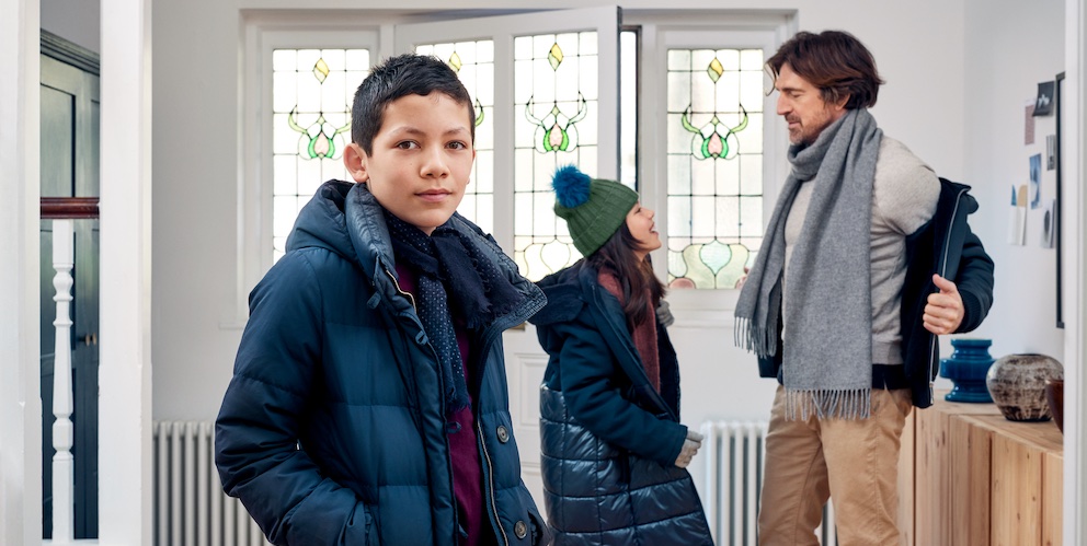 Eine Familie steht an der Tür des Hauses und der Sohn schaut in die Kamera.