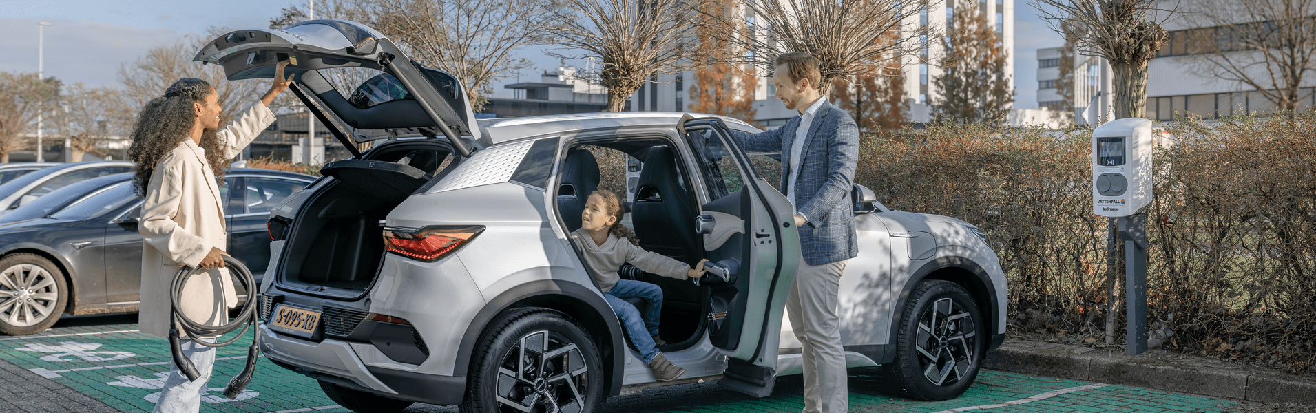 Familie parkt mit E-Auto auf Parkplatz.