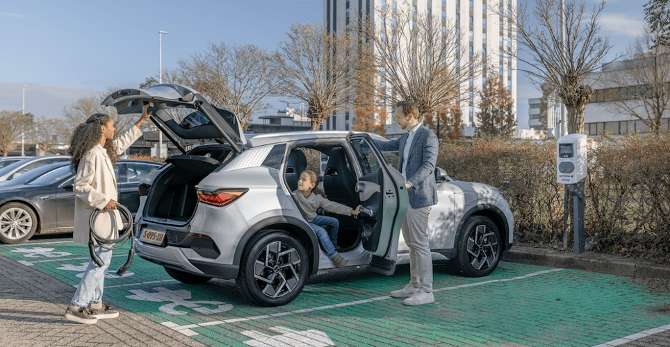 Familie parkt mit E-Auto auf Parkplatz.