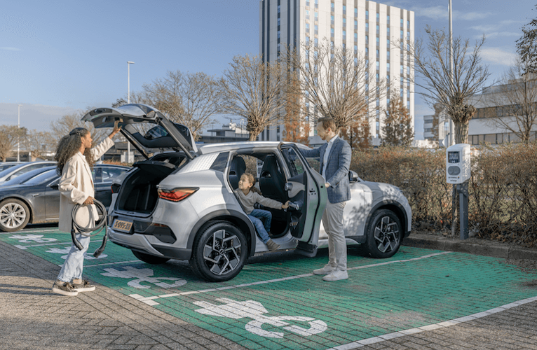 Familie parkt mit E-Auto auf Parkplatz.