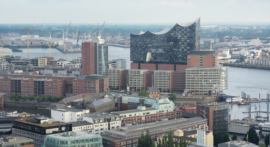 Blick über die Skyline von Hamburg mit der Elbphilharmonie  im Vordergrund und dem Hafen dahinter.