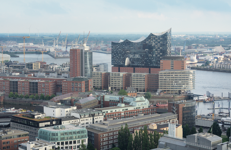 Blick über die Skyline von Hamburg mit der Elbphilharmonie  im Vordergrund und dem Hafen dahinter.