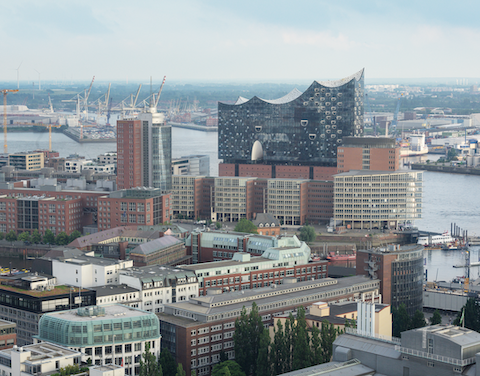 Blick über die Skyline von Hamburg mit der Elbphilharmonie  im Vordergrund und dem Hafen dahinter.